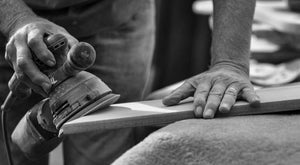 Black and white closeup of hands sanding wood. 