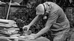 Black and white picture of Greg sanding serving trays. 